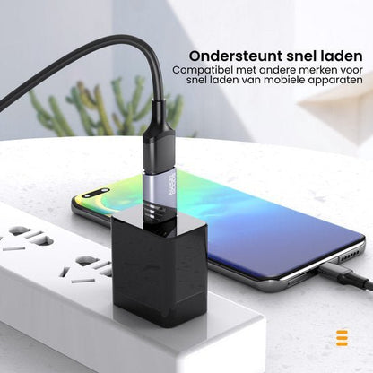 Mobiele telefoon op een tafel opgeladen met een zwarte USB-lader en kabel in stopcontact