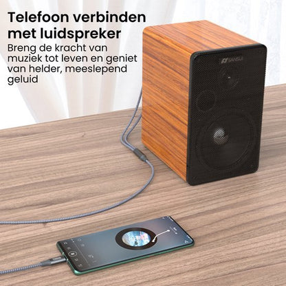 Luidspreker met houten kast verbonden met smartphone via kabel op houten tafel.