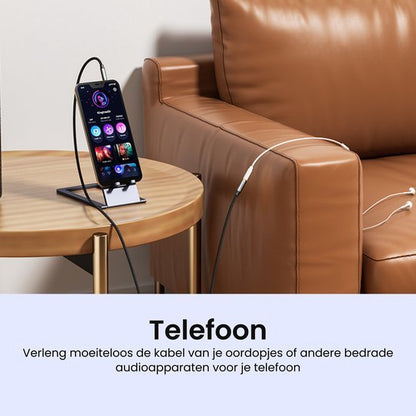 Telefoon op standaard met aangesloten kabel en oordopjes naast bruin leren bank.