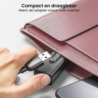 Hand steekt compacte zwarte adapter met usb-kabel in roze leren tas voor draagbaarheid