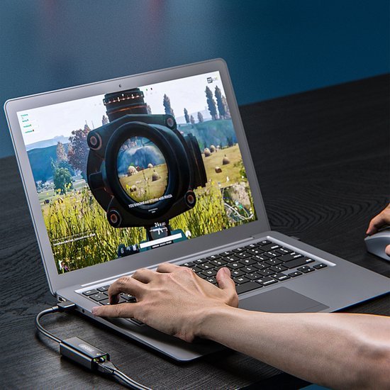 Hand bedient laptop met gameplay zichtbaar op scherm en een verbonden randapparaat