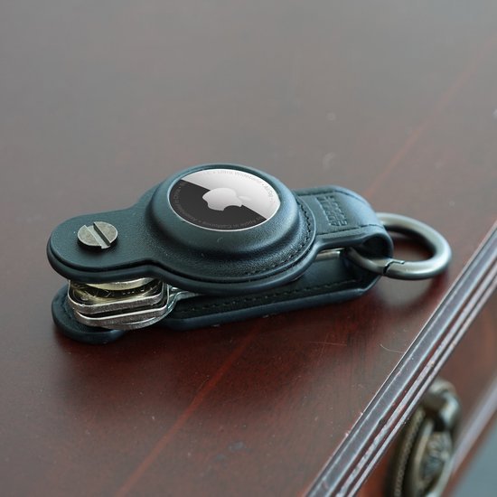 zwart leren sleutelhanger met metalen ring en ingebouwde Airtag houder liggend op houten oppervlak