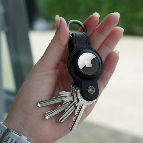 Hand houdt sleutelhanger met meerdere sleutels en ronde metalen Apple accessoire zichtbaar