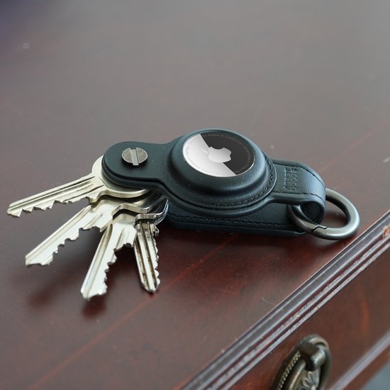 sleutels met leren sleutelhouder en zwarte accessoire op houten tafel gelegd