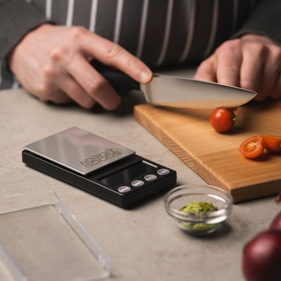 Hand snijdt kerstomaatjes op houten plank naast digitale keukenweegschaal AdroitGoods