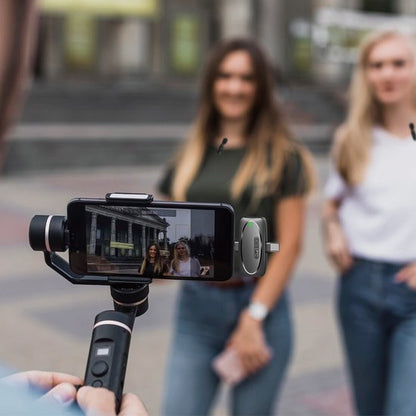 Twee vrouwen poseren buiten terwijl een smartphone op een stabilisator hen filmt