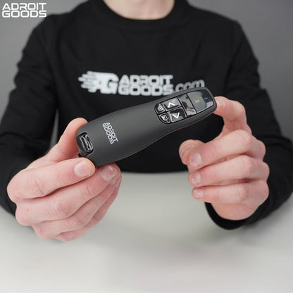 Hand houdt compacte zwarte presentatiepointer met knoppen en Adroit Goods logo vast