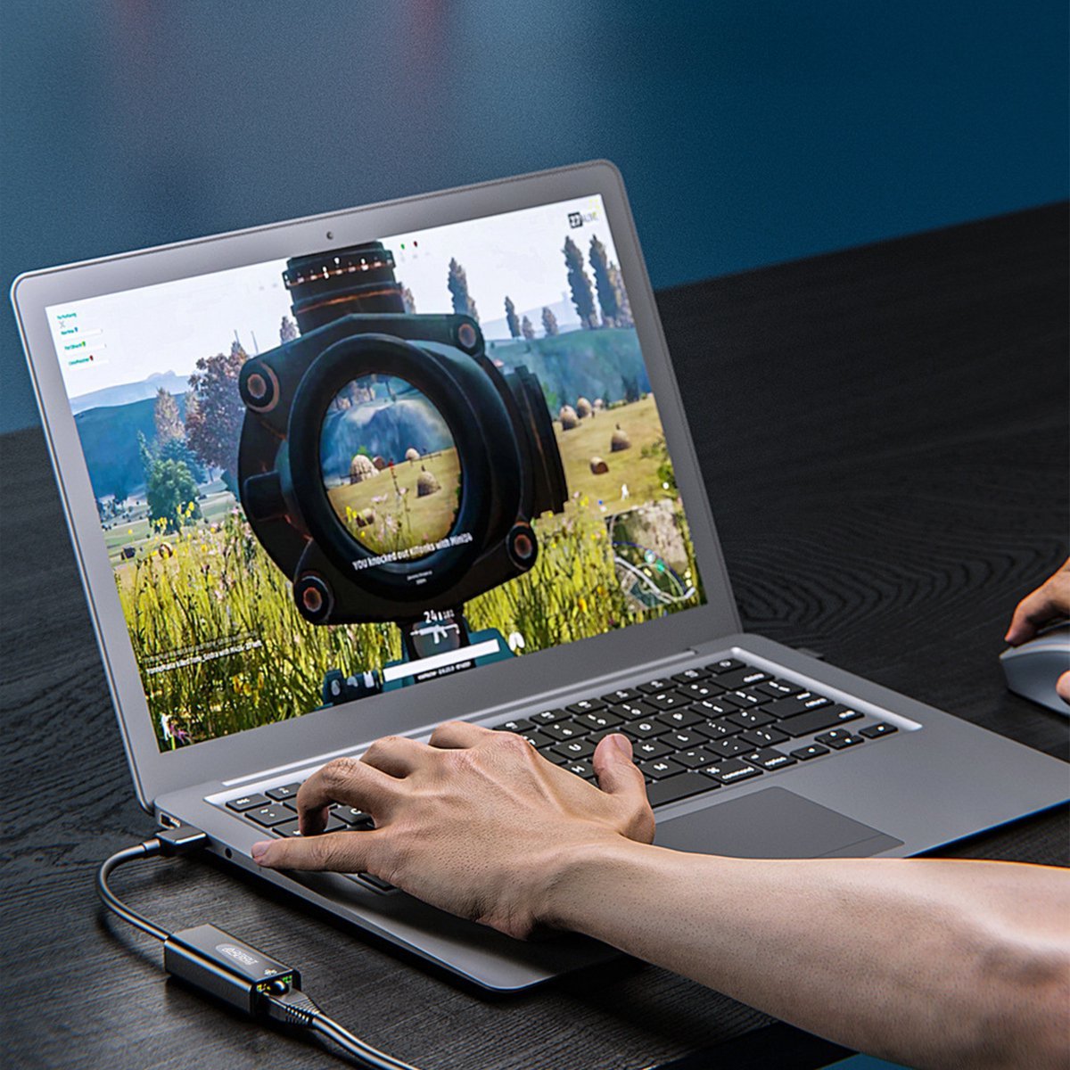 Hand bedient laptop met schietspel zichtbaar op scherm in realistische spelomgeving