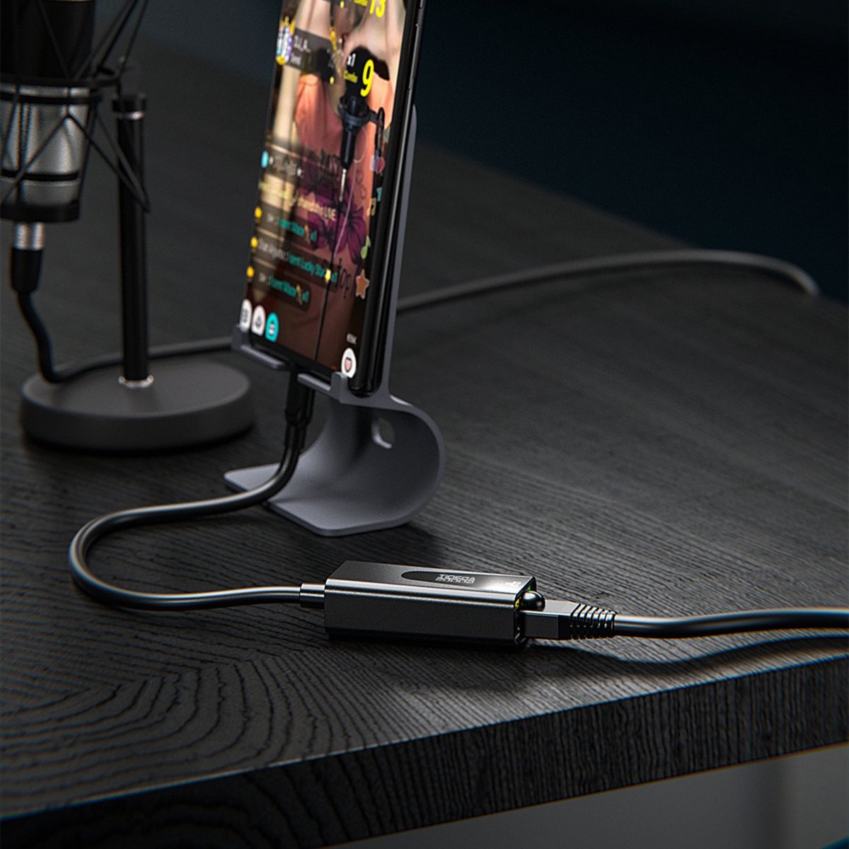 Telefoon op standaard met verbonden kabel en een klein zwart apparaat op een zwart bureau