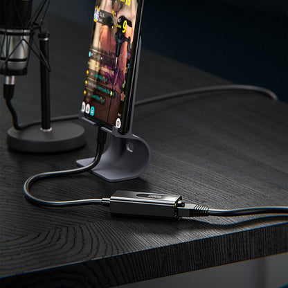 Telefoon op standaard met verbonden kabel en een klein zwart apparaat op een zwart bureau