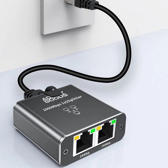 Zwarte netwerksplitter aangesloten op wandcontactdoos met twee ethernetpoorten zichtbaar.