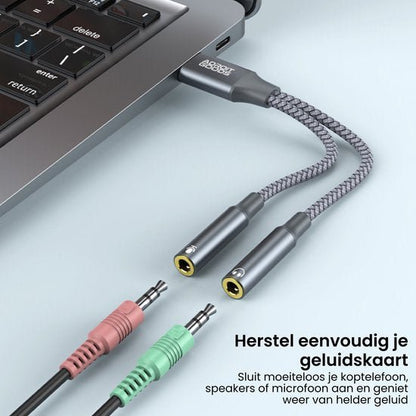 Grijs gevlochten audiokabel met twee 3,5 mm jacks verbonden met laptoppoort.
