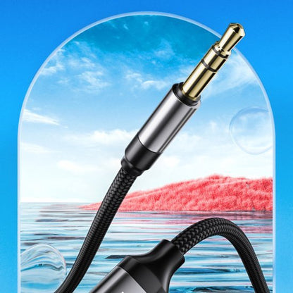 Zwarte geweven kabel met gouden 3,5 mm audiostekker en blauwe lucht en water op achtergrond