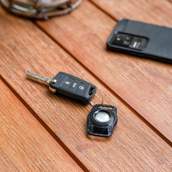 Autosleutel en sleutelhanger op houten tafel naast zwarte smartphone