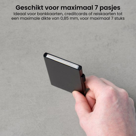 Hand die een compacte zwarte kaartetui vasthoudt tegen een grijze achtergrond