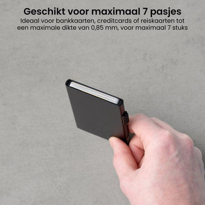 Hand die een compacte zwarte kaartetui vasthoudt tegen een grijze achtergrond
