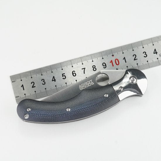 Opgevouwen zakmes met zwart handvat en metalen lemmet naast metalen liniaal van 15 cm