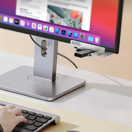 Monitor met USB-hub bevestigd aan zilveren standaard en toetsenbord op bureau in gebruik