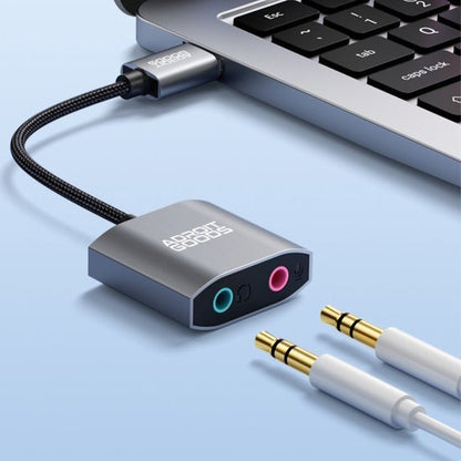 Adapter met twee audiopoorten aangesloten op laptop via USB-C kabel met twee 3,5 mm stekkers naast elkaar