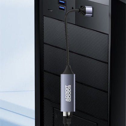 USB-verlengkabel met metalen behuizing en AdroitGoods logo aangesloten op pc achterkant