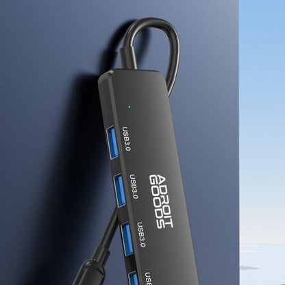 zwarte USB-hub met meerdere poorten en AdroitGoods logo tegen blauwe achtergrond