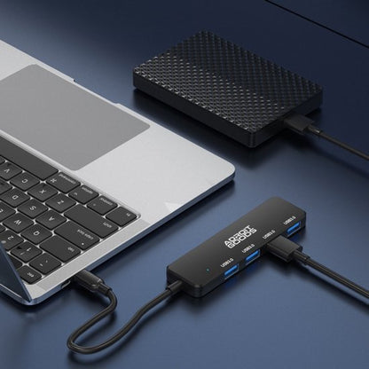 Zwarte USB-hub met meerdere poorten aangesloten op laptop en externe schijf op donker oppervlak