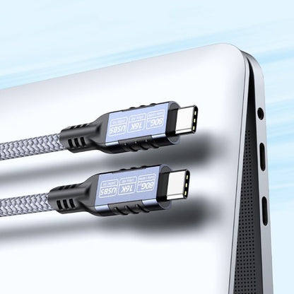 Twee stevige USB-C-kabels met gevlochten omhulsel naast een zilvergrijze laptoppoort