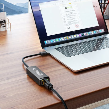 Laptop op houten bureau met een aangesloten zwarte USB-C adapter en netwerkkabel