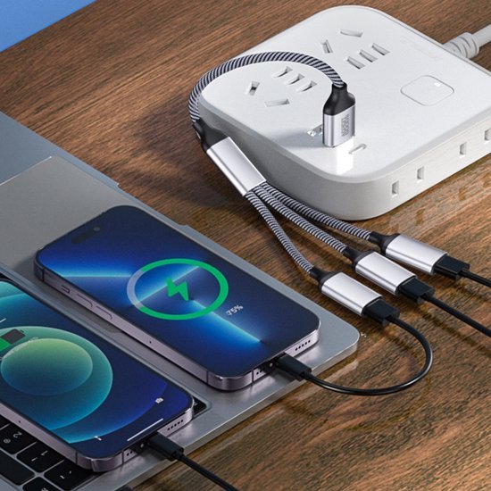 opladen van twee smartphones tegelijk via een witte stekkerdoos met meerdere kabels op houten oppervlak