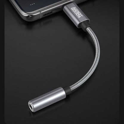 Zilverkleurige stevige audioadapter kabel aangesloten op een smartphone in een moderne setting