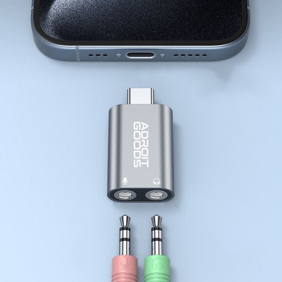 Zilverkleurige AdroitGoods USB-C adapter met twee 3,5 mm audiopoorten naast smartphone poort