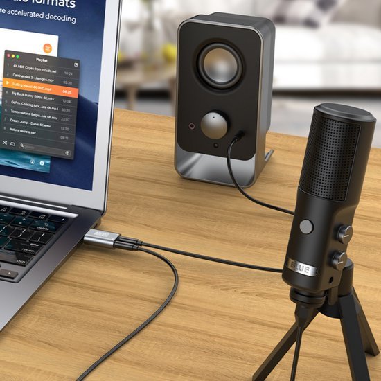 Laptop verbonden met zwart microfoon en luidspreker op houten bureau in lichte kamer