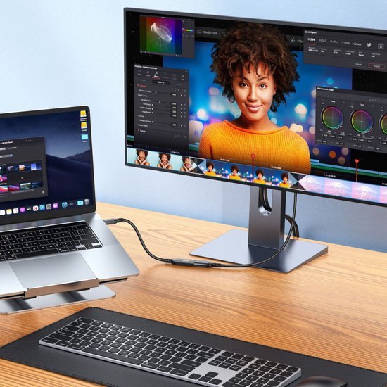 werkplek met laptop en grote monitor met kleurcorrectie software op houten bureau
