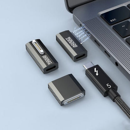 Zwarte magnetische kabeladapter en connectoren naast een laptop met blauwe verbindingslijnen zichtbaar