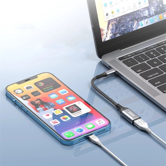 Smartphone verbonden met een laptop via een kort, gevlochten oplaadkabeltje op een glanzend oppervlak
