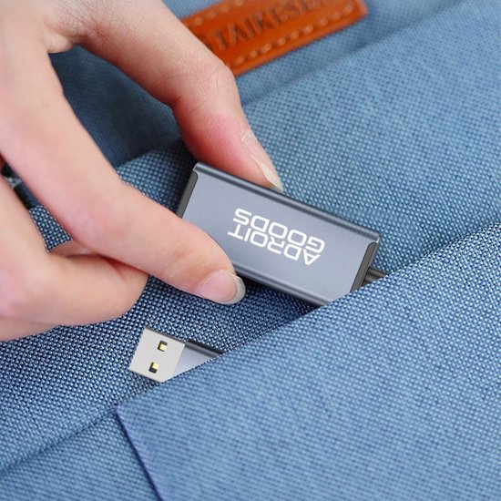 Hand die USB-stick met logo AdroitGoods in een blauwe stoffen tas stopt.