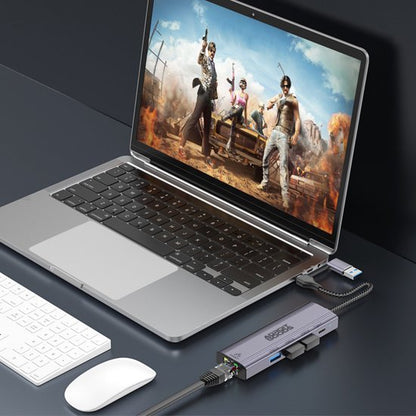 Laptop met open beeldscherm waarop een actiespel speelt, aangesloten op meerdere externe apparaten.